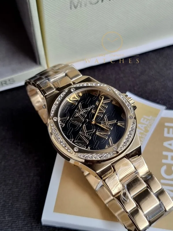 MK7404 שעון מייקל קורס יבואן רשמי 100% מקורי לאישה | דגם זהב בלוח שחור מיוחד ממותג MK | שעון אלגנטי כולל שנתיים אחריות פלאנט טיים | MK7404 Michael Kors Lennox Gold-Tone Watch